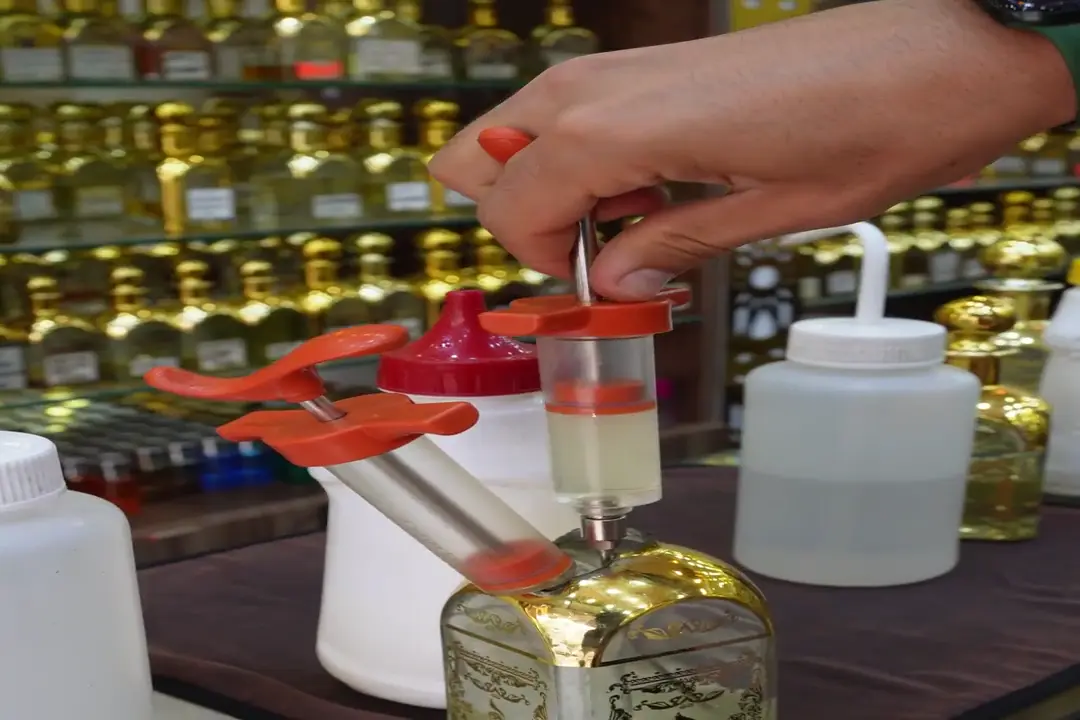 تعبئة عطر زيتي من الخزان في قارورة داخل المحل